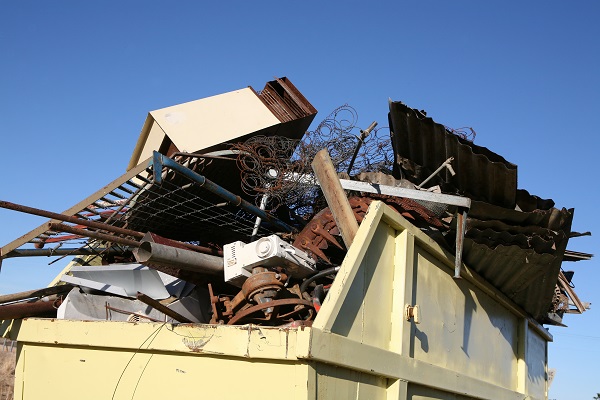 Yellow steel waste skip full of household rubbish